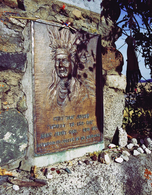 Bronze plaque of Chief Joseph, depicting his portrait and inscription, surrounded by stones and nature.