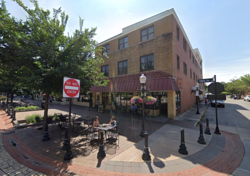 A street corner with a café, outdoor seating, and a "Do Not Enter" sign under a clear blue sky.