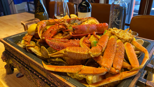 A large seafood platter featuring various crabs, lobster, clams, and garnished with lemon slices.