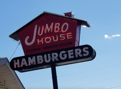 Sign for Jumbo House featuring ice cream, broasted chicken, and hamburgers against a clear blue sky.