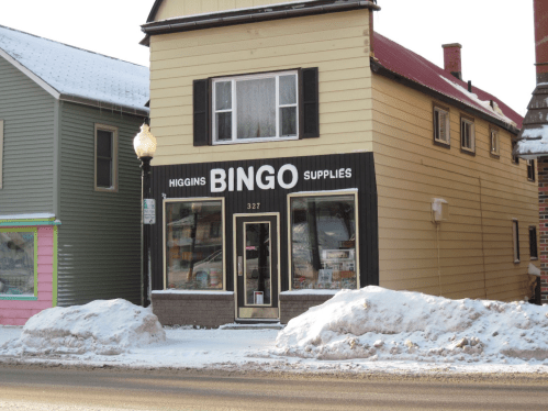 A two-story building with a sign reading "Higgins BINGO SUPPLIES" in a snowy setting.