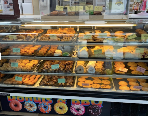 A display case filled with various baked goods, including cookies, donuts, and pastries, all labeled with colorful tags.