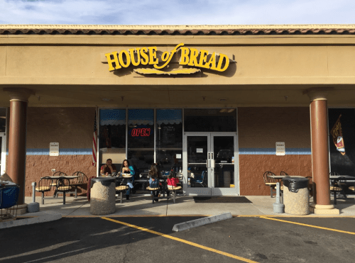 Exterior of House of Bread bakery with outdoor seating and an "Open" sign visible.