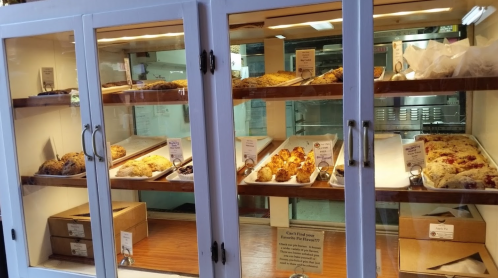 A display case filled with various baked goods, including pastries and scones, neatly arranged on trays.
