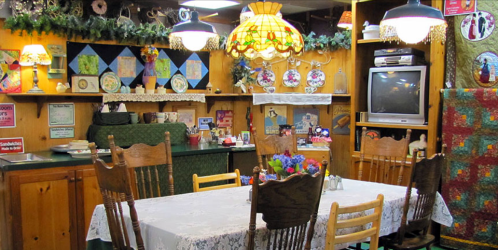 Cozy dining room with a wooden table, vintage decor, colorful lamps, and a warm, inviting atmosphere.
