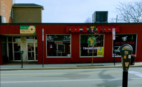 A red storefront with "Fox's Pizza" sign, open hours displayed, and a parking meter in front.