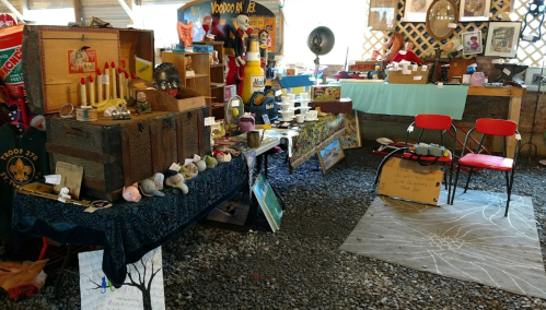 A vibrant market stall filled with eclectic items, including vintage decor, crafts, and colorful chairs.