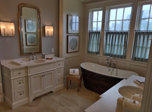A stylish bathroom featuring a freestanding tub, double sink vanity, and large windows with elegant curtains.