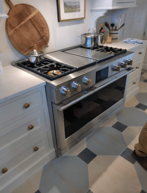 A modern kitchen with a stainless steel stove, pot on the burner, and a wooden cutting board on the wall.