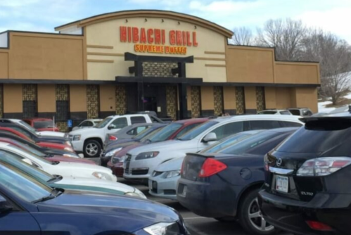 Exterior of Hibachi Grill restaurant with a busy parking lot filled with various cars.