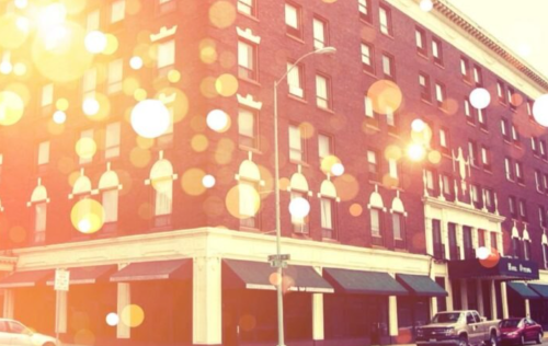A vintage-style brick building with decorative awnings, softly illuminated by bokeh lights in the foreground.