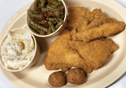 A plate with fried fish fillets, green beans, mashed potatoes, and two cornbread muffins.