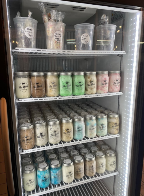A refrigerator filled with jars of colorful desserts, labeled with various flavors and topped with decorative lids.