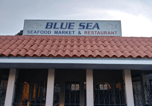 Sign for "Blue Sea Seafood Market & Restaurant" on a building with a red tiled roof.