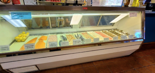 A display case filled with various types of fish and seafood, with price labels and lemons on top.