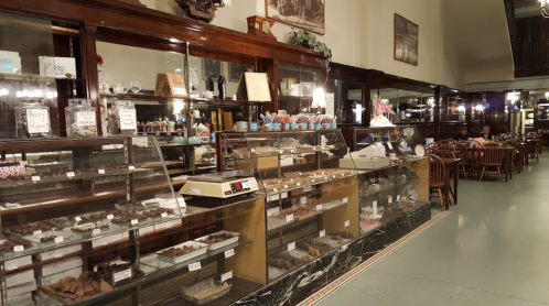 A vintage candy shop display filled with various chocolates and sweets, with wooden furniture in the background.