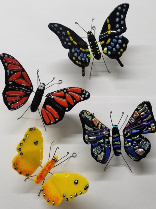 Colorful decorative butterflies made of various materials, featuring vibrant red, yellow, and blue designs.