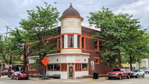 Historic brick building with a turret, surrounded by trees, featuring a café and outdoor seating area.