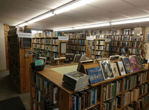 A cozy bookstore with wooden shelves filled with books and a central display table. Warm lighting enhances the inviting atmosphere.