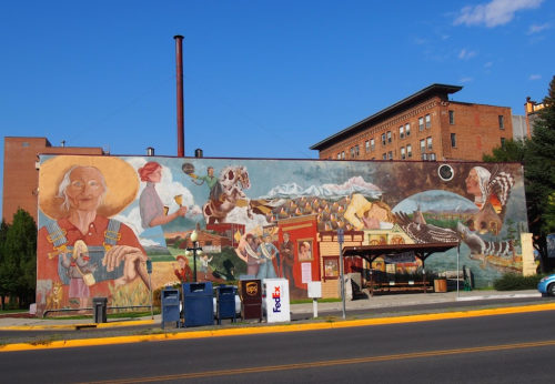 A colorful mural depicting various scenes, including people, animals, and landscapes, on a building wall.