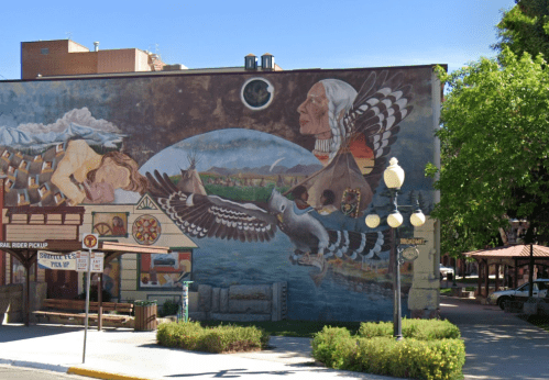 A colorful mural depicting a woman, birds, and landscapes, blending nature and culture in an urban setting.