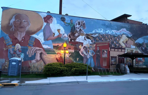 A colorful mural depicting various scenes, including a farmer, a woman with a beer, and mountains in the background.