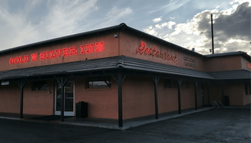 Exterior of the Gold N Silver Inn restaurant, featuring a neon sign and a cloudy sky in the background.