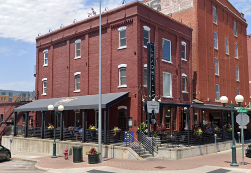 A red brick restaurant with outdoor seating, featuring a sign that reads "Leadbelly," located on a city street.