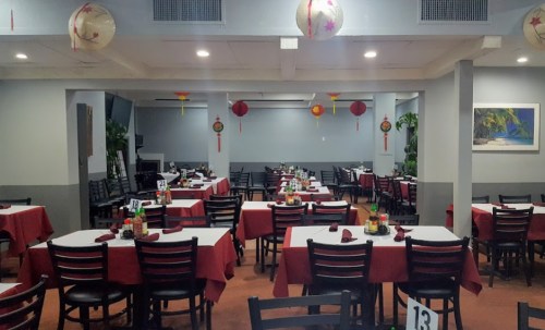 Interior of a restaurant with red tablecloths, black chairs, and decorative lanterns hanging from the ceiling.
