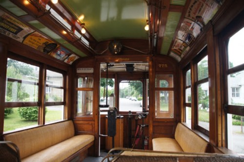 Interior of a vintage streetcar, featuring wooden benches and vintage advertisements on the walls.