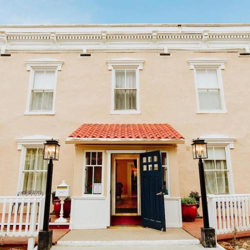 A charming building with a light-colored facade, red tile roof, and a blue door, flanked by lanterns.