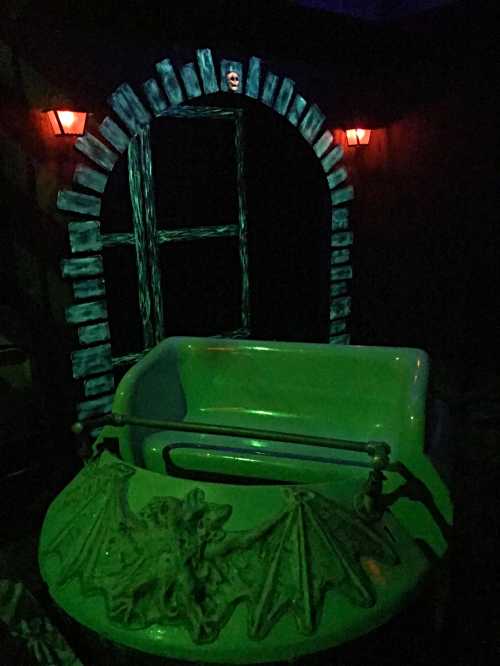 A dimly lit scene featuring a green bathtub with a dragon design, set against a dark, arched doorway and glowing lanterns.