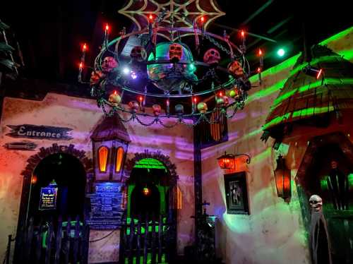 A spooky entrance with a chandelier of skulls, cobwebs, and eerie lighting, creating a haunted atmosphere.