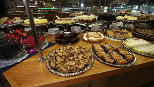 A variety of desserts displayed on a wooden table, including cakes, pastries, and fresh fruit.