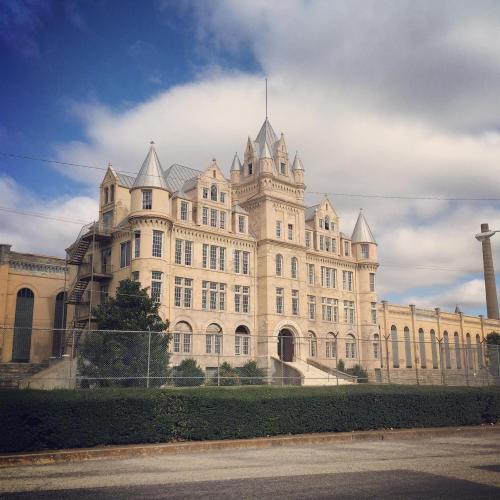 Historic building with a castle-like design, featuring turrets and a large entrance, set against a cloudy sky.