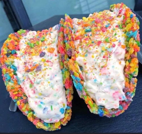 Two colorful dessert tacos filled with creamy ice cream and topped with rainbow sprinkles.