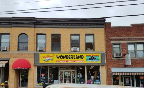A storefront with a bright "WONDERLAND" sign, featuring comics, toys, and games, alongside other shops.