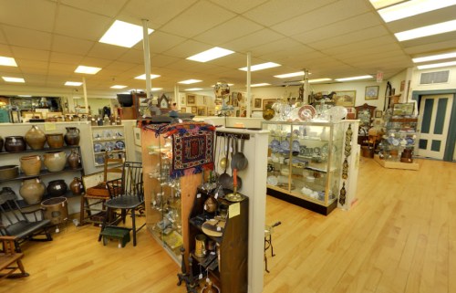 A spacious antique shop filled with various collectibles, display cases, and wooden furniture.