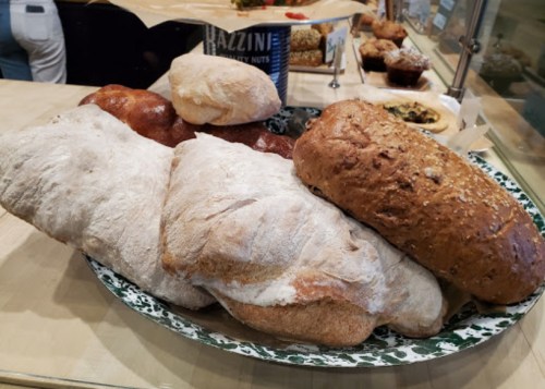 A variety of freshly baked breads on a decorative plate, including loaves and rolls in different shapes and colors.