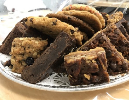 A plate of assorted baked goods, including brownies, cookies, and bars, arranged attractively.