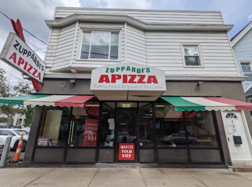Exterior of Zuppardi's Apizza, a family-owned pizzeria with a red and green awning and a sign displaying its name.