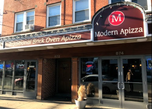 Exterior of Modern Apizza restaurant, featuring a brick facade and a sign with the name and tagline about traditional pizza.