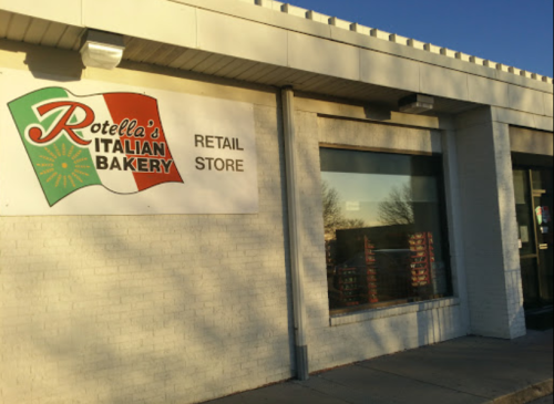 Exterior of Rotella's Italian Bakery retail store, featuring a colorful sign with the bakery's name and logo.