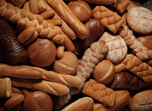 A variety of freshly baked breads, including loaves, rolls, and pastries, arranged in a textured display.