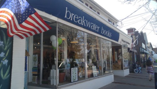 Exterior of Breakwater Books with an American flag, showcasing large windows and a welcoming entrance.