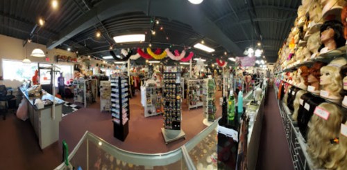 A wide view of a vibrant wig and costume shop filled with colorful wigs, accessories, and displays.
