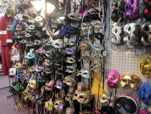 A display of various decorative masks in different colors and styles hanging on a pegboard.