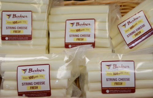 Packages of Baker brand string cheese, labeled "Fresh," stacked in a basket.