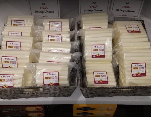 Baskets of individually packaged fresh string cheese sticks on display in a store.