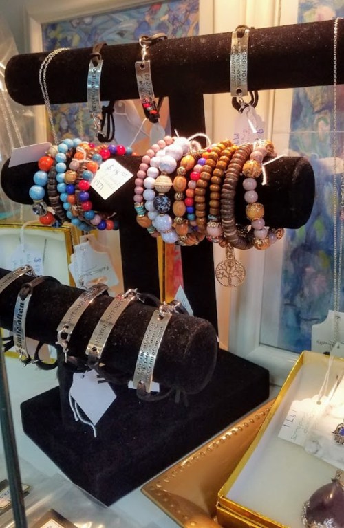 A display of colorful bracelets and necklaces on a black velvet stand, showcasing various styles and materials.
